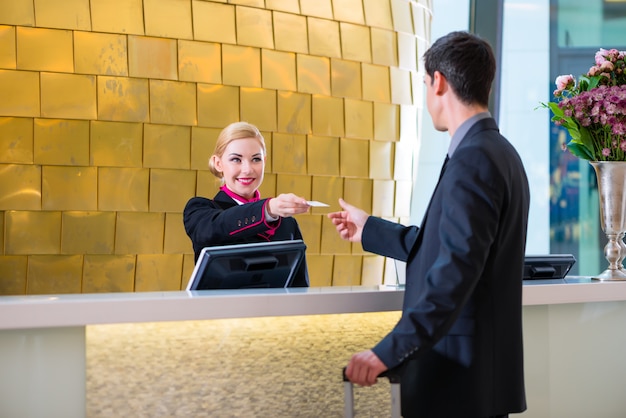 Hotel receptionist check in man giving key card