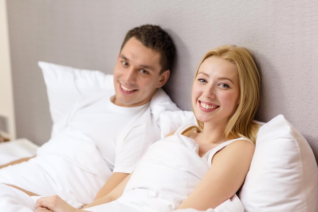 hotel, reizen, relaties en geluk concept - gelukkig paar in bed