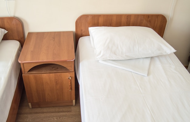 Photo hotel room with two empty single beds and bedside tables, the concept of the hotel business.