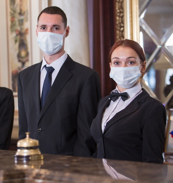 The hotel staff serves guests in medical masks