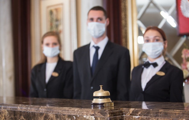 The hotel staff serves guests in medical masks