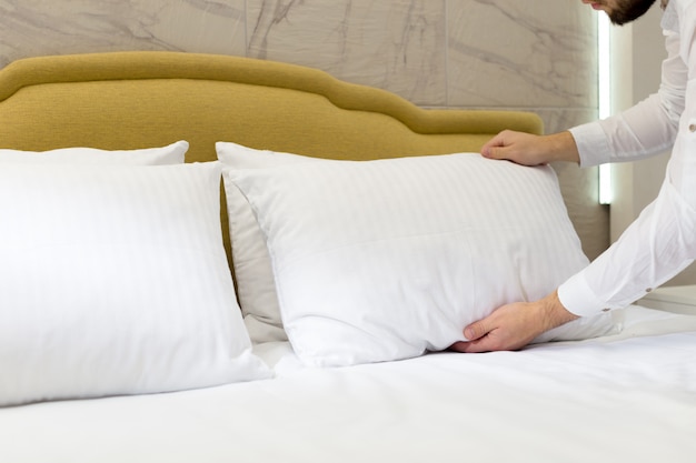 Hotel staff setting up pillow on bed