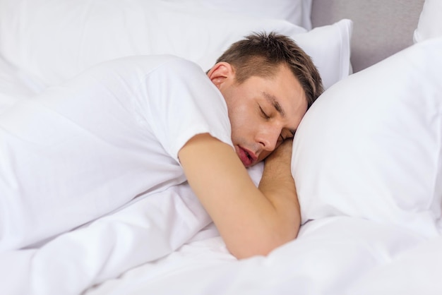 hotel, travel and happiness concept - handsome man sleeping in bed