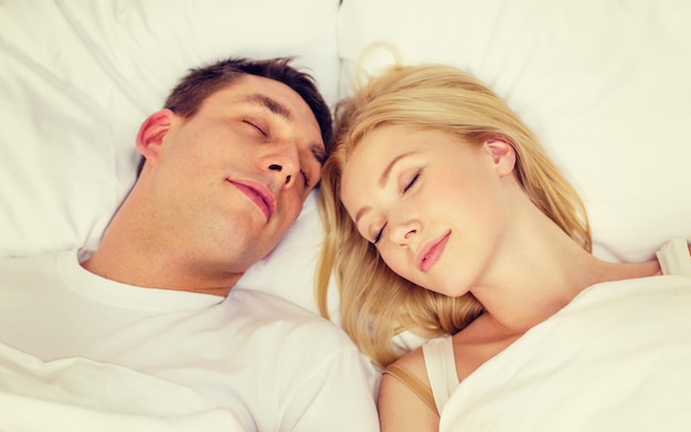 ホテル、旅行、人間関係、そして幸福の概念-ベッドで寝ている幸せなカップル