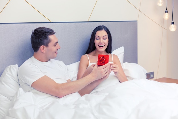 hotel, travel, relationships, holidays and happiness concept - man giving woman little red gift box