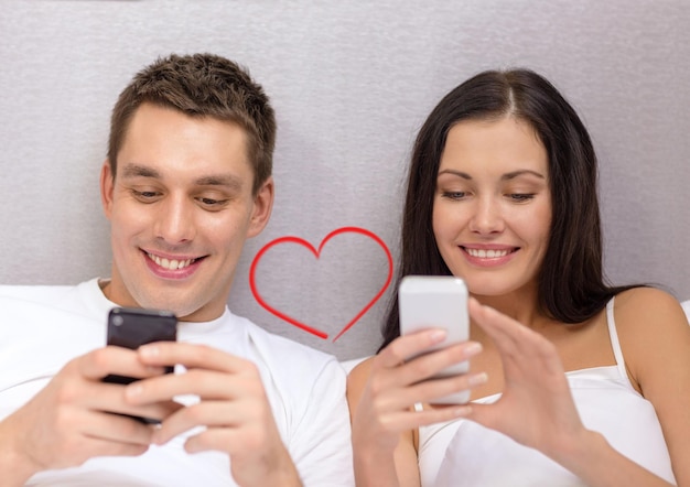 호텔, 여행, 관계, 기술, intermet 및 행복 개념 - 스마트폰으로 침대에서 웃는 커플