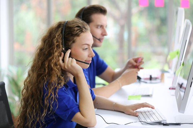 Photo hotline support service female call center operator in headset working with laptop