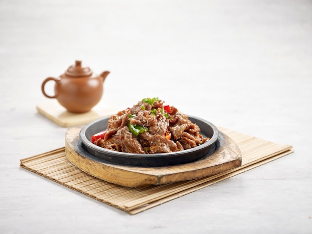 HotPlate Mutton with Cumin in a dish isolated on wooden board side view on grey background