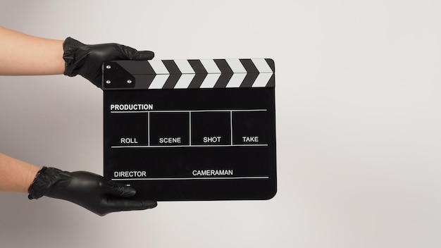 Hou in de hand een zwarte clapperboard of filmleiste en draag een zwarte latex handschoen op een witte achtergrond