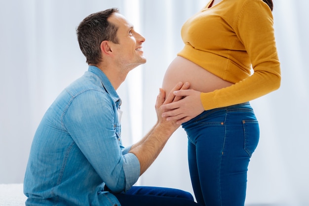 Hou van jou. Knappe man die geluk voelt en het hoofd opheft terwijl hij naar zijn vrouw kijkt