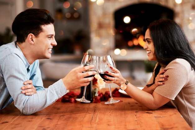 Hou van wijn en paar proost op valentijnsdag date thuis met glimlach romantiek en bokeh Datum nacht man en vrouw aan tafel in woonkamer valentijnsviering en gelukkige relatie samen