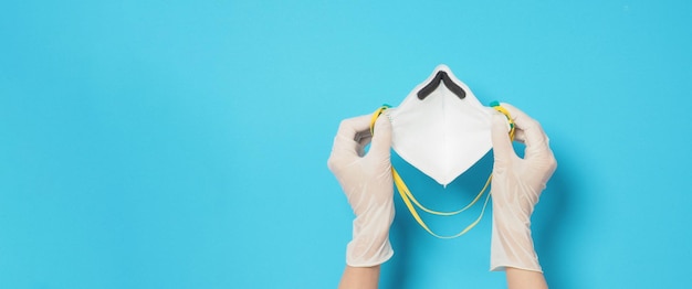 Houd n 95 gezichtsmasker vast en draag witte medische handschoenen op blauwe achtergrond