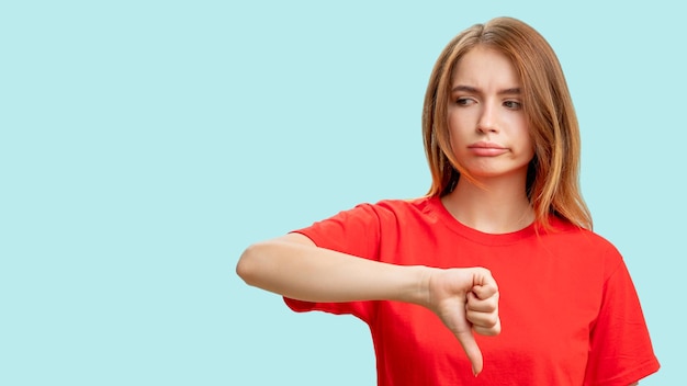 Houd niet van gebaar Slecht idee Portret van teleurgestelde vrouw in rode tshirt kritiek met duim naar beneden geïsoleerd op blauwe kopie ruimte achtergrond Niet cool Laat het