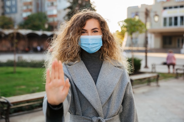 Foto houd sociale afstand. vrouw in virusbescherming gezichtsmasker met gebaar stop infection. coronavirus covid-19 pandemie en gezondheidszorgconcept.