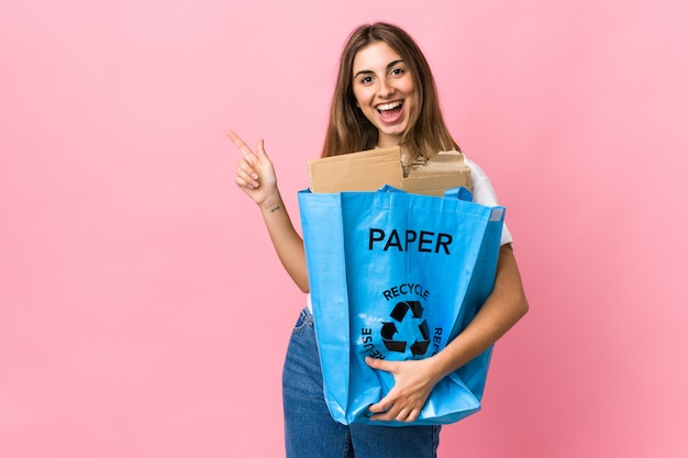 Houden een recycling zak vol papier te recyclen over geïsoleerde roze wijzende vinger naar de zijkant