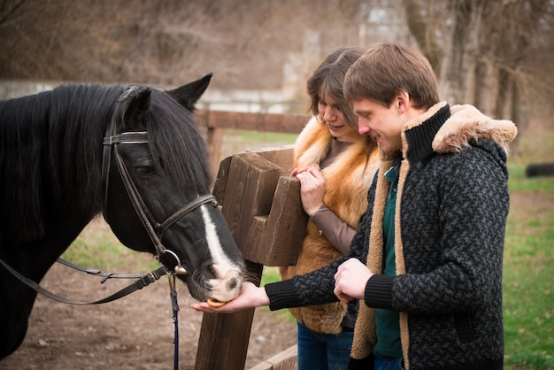 Houdend van paar met een paard op boerderij in een de herfst bewolkte dag.