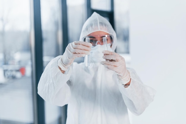 Houdt reageerbuizen Portret van vrouwelijke arts wetenschapper in laboratoriumjas defensieve brillen en masker