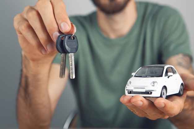 Houdt sleutels en een auto in zijn handen