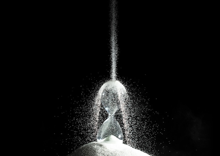 Photo 砂時計は黒い背景の上に白い砂の上に時間の砂を追加します 白い砂時計ではより多くの時間が表示されます 締め切りは時間管理を拡張します 希望の概念時間ガラスの生活時計が過ぎていきます