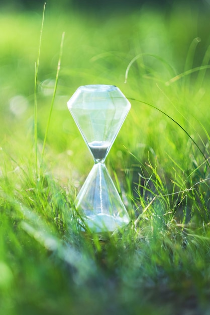 An hourglass on a background of green grass.