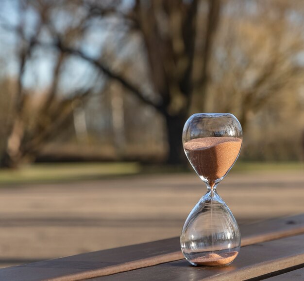 An hourglass on a bench in a spring park.