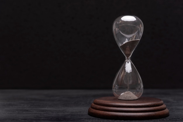 Hourglass on black background. Urgency and outcome of time. Time management.