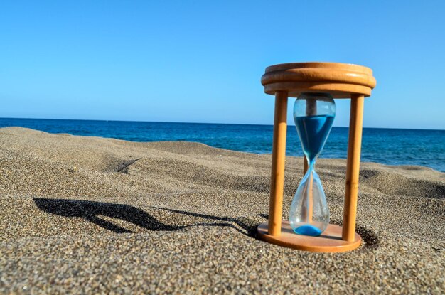 Foto orologio a sabbia sulla spiaggia di sabbia