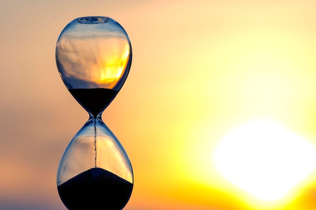 Hourglass counts the length of time against the background of the evening sun