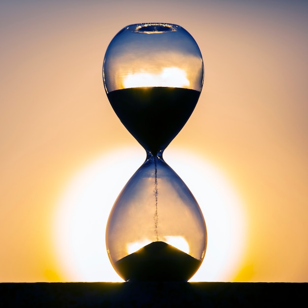 Hourglass counts the length of time against the background of the evening sun