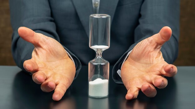 Hourglass next to the hands of a business man.