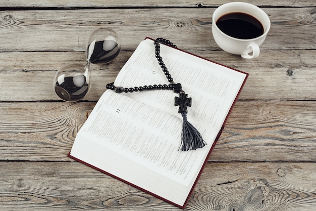 Hourglass and open bible with coffee cup