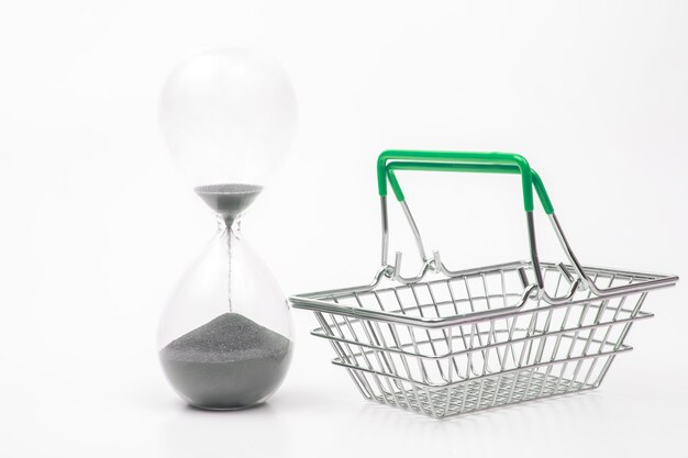 Hourglass and shopping cart for market groceries on white background
