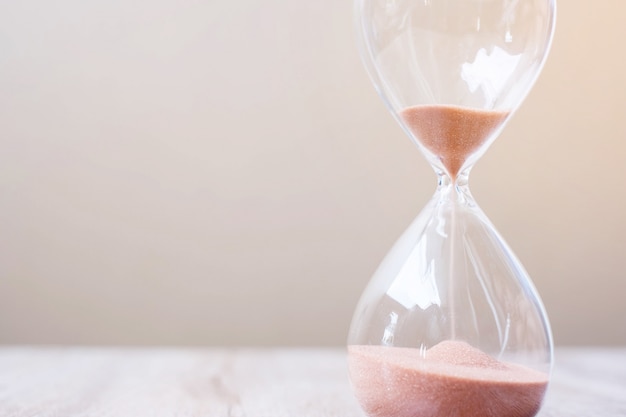 Hourglass on table, Sand flowing through the bulb of Sandglass measuring the passing time. countdown, deadline, Life time and Retirement concept