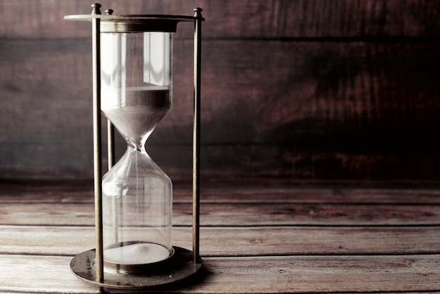 Hourglass on table, sand flowing through the bulb of sandglass