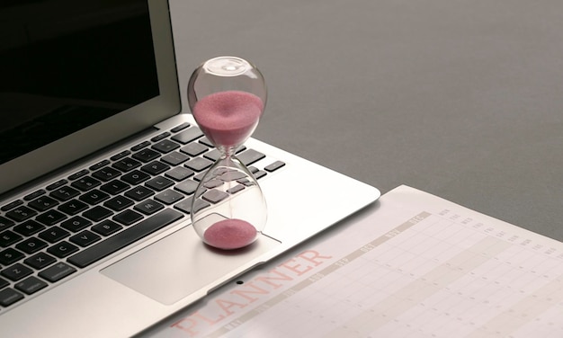 Hourglass on top of computer laptop and calendar planner