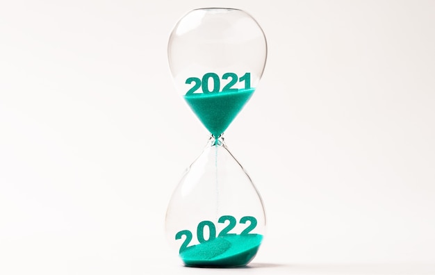 2021年から2022年に変更するための青い砂の砂時計、カウントダウンと準備メリークリスマスと新年あけましておめでとうございますのコンセプト。