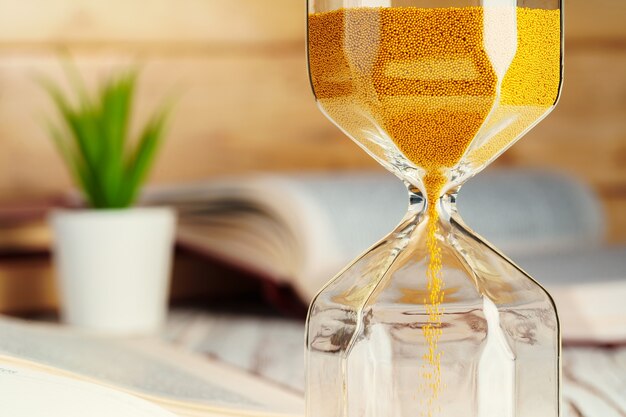 Hourglass with sand close up on wooden background