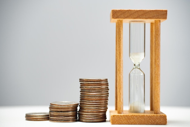 An hourglass with a stack of coins nearby Expiration Time for investment and growth