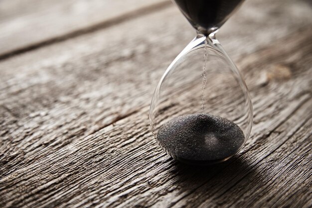 Photo hourglass on wooden background close up urgency and running out of time concept