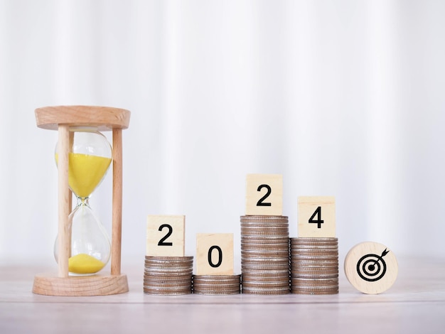 Photo hourglass and wooden block with number 2024 on stack of coins the concept of saving money manage time to business achievement goal financial investment and business growing in new year 2024