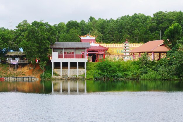 House by lake and buildings against sky