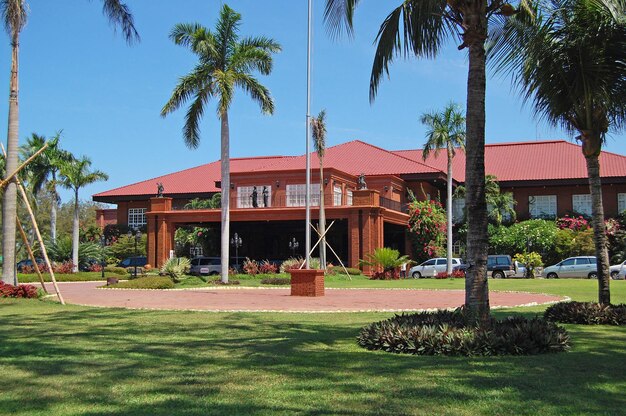 House by palm trees and lawn against sky