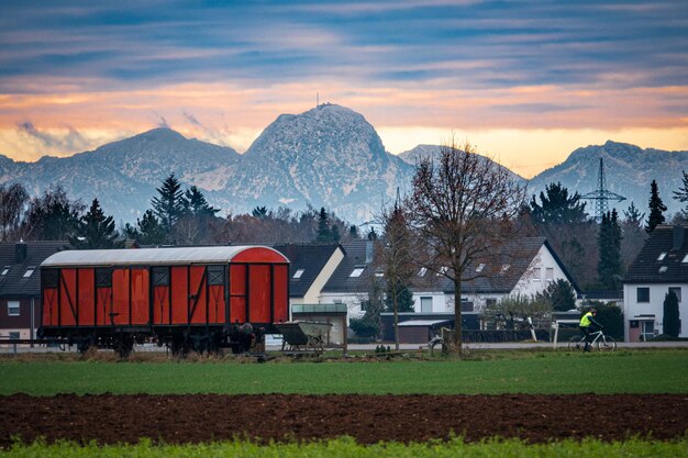 House by snowcapped mountains against sky during sunset