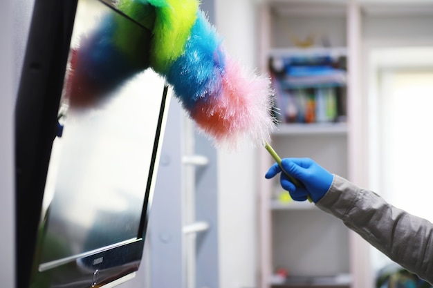 Concetto di pulizia della casa. pulisci la polvere dalle superfici. trattamento disinfettante delle maniglie delle porte tv elettriche. trattamento sanitario a casa in quarantena.