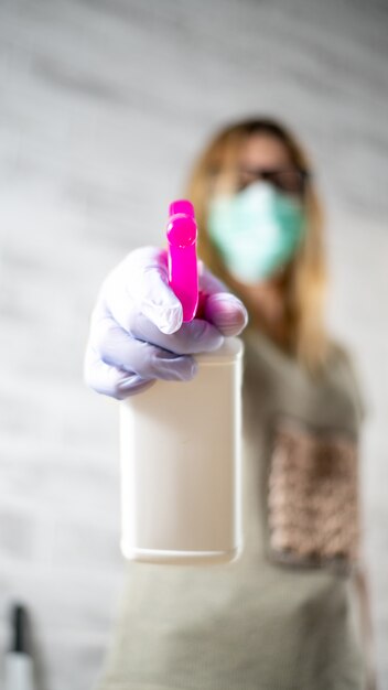 Foto la mano di pulizia della casa con la bottiglia della ragazza detersiva liquida tiene il disinfettante dello spruzzo