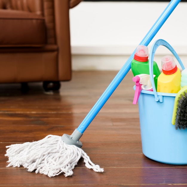 House cleaning products in blue bucket on hardwood floor