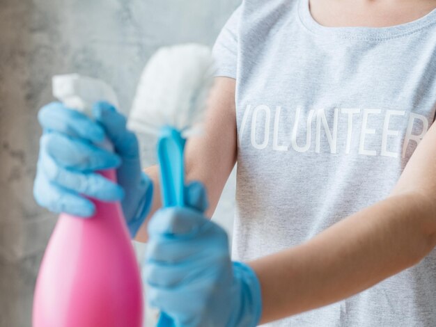 ハウスクリーニングボランティア女性の胴体とアトマイザーとブラシ青いゴム手袋の手