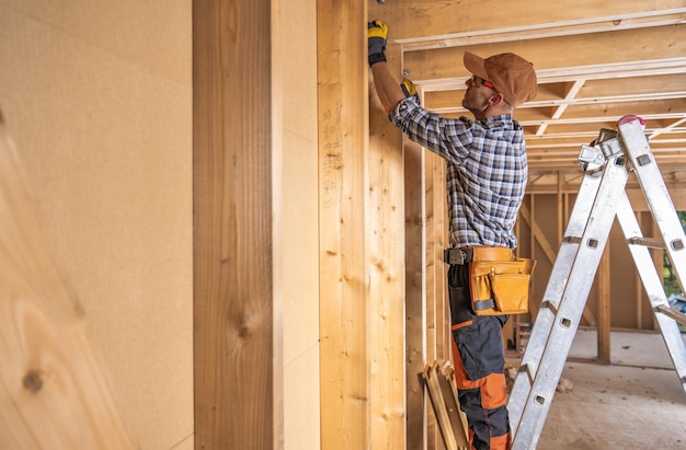 Foto il supervisore della costruzione della casa controlla le travi di legno principali