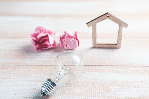 House, crumpled paper and a light bulb on the table