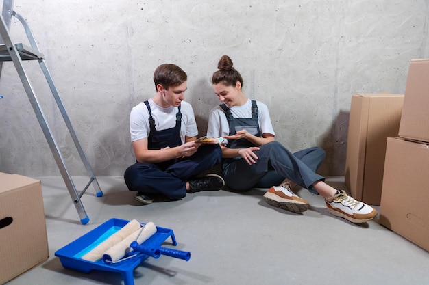 House decoration diy renovation concept happy couple sitting on floor in empty room of new home plan